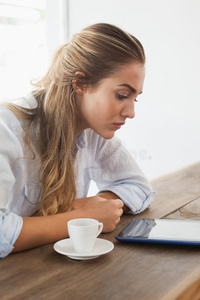金发美女用平板电脑喝咖啡