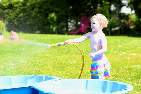 小女孩在花园里玩水管