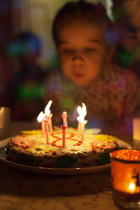 吹熄生日蛋糕上的蜡烛的小女孩