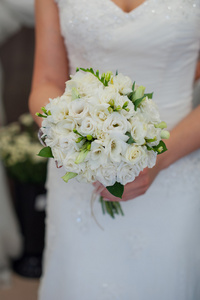 新娘抱着白色美丽的婚礼花束