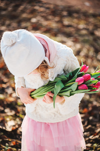 可爱的孩子女孩与女人一天的步行在春天的郁金香花束
