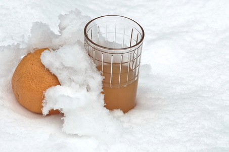 橘子水果和橙汁在花园里的雪堆里冷藏