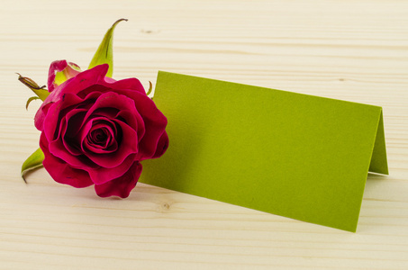 玫瑰花朵与空白的邀请卡上木制背景