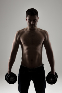 较强的健身男人与肌肉的低关键肖像