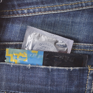 各种避孕套各种不同的避孕套在蓝色牛仔裤的口袋里照片