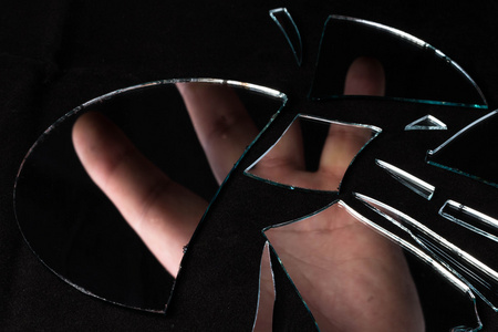 镜子在许多片断被粉碎了女孩触摸破碎的镜子破碎的镜子玻璃碎片女人看