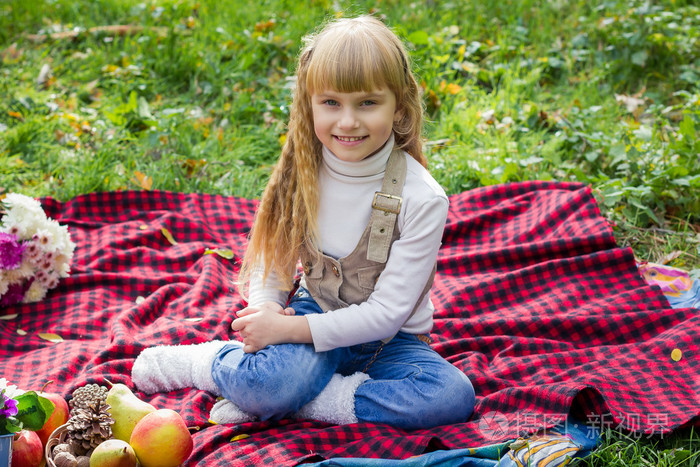 美丽年轻小孩坐在一个红色的格子上.可爱的孩子微笑着鲜艳的花照片-正