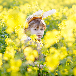 快乐的小小孩男孩与复活节兔子耳朵，庆祝复活节