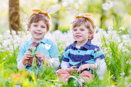 两个小男孩头戴复活节兔子耳朵和吃巧克力