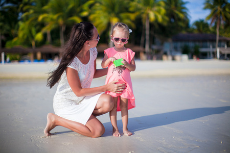 母亲和在海滩度假的可爱女孩图片