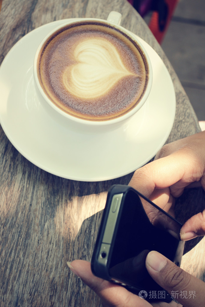 老式的拿铁艺术咖啡与智能手机