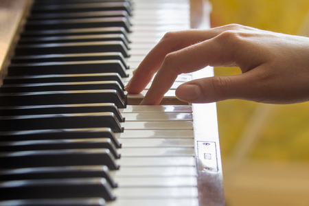 女孩的右手的手指握着压注的钥匙在钢琴上照片