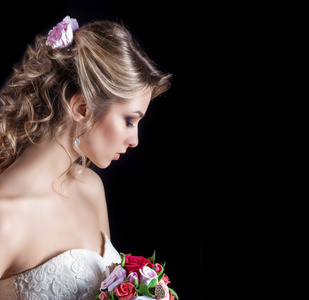 温柔快乐微笑的美丽的女孩在白色的婚纱礼服与婚礼花束的肖像牵手美丽的头发和明亮的化妆，摄影工作室