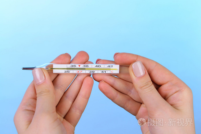 女手拿温度计在蓝色背景照片-正版商用图片1icau9-摄图新视界