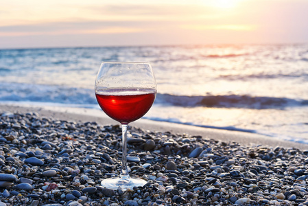 浪漫 glass 的酒坐在沙滩上在七彩的晚霞，玻璃夕阳红葡萄酒 红酒海海洋沙滩上的 云天空背景