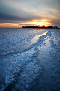冬季景观与冰冻的湖面和落日的天空。组成