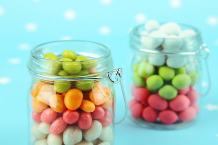 多色糖果的玻璃罐在彩色背景上