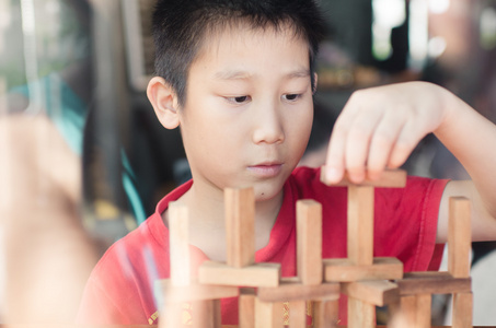 亚洲男孩玩木头游戏Jenga。