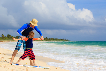 父亲和小儿子学习冲浪的海滩