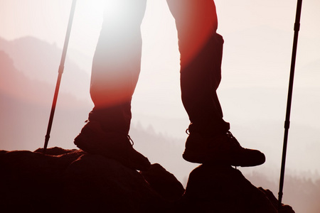男人的徒步旅行者腿和波兰人站在山顶岩石山