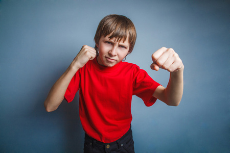 男孩，少年，十二年中一件红色的衬衫，显示出他的拳头