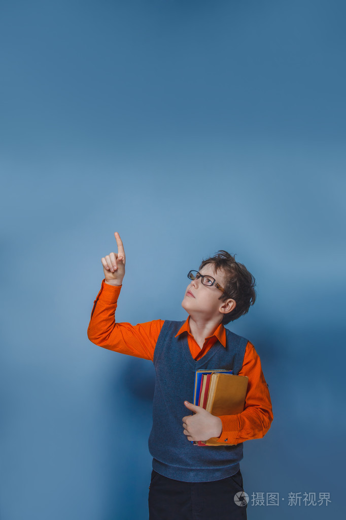 欧洲人的小男孩的十年中眼镜竖起大拇指,蓝色背景上的那本书的想法
