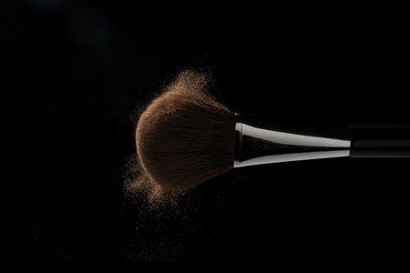 水平的特写照片的化妆刷与米色粉在黑色背景上孤立的议案