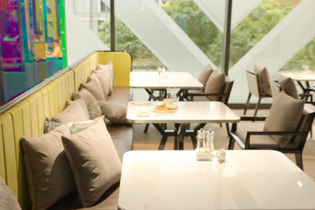 抽象的模糊餐厅，与模糊绿色大树外中背景的窗口可见