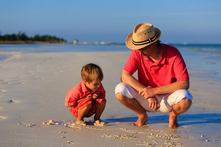 父亲和儿子在夏天的海滩上绘图图片