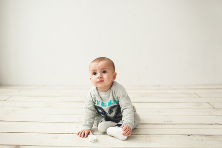 一岁可爱的小宝贝男孩坐在木地板上
