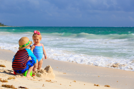 在热带的海滩上玩沙子的孩子