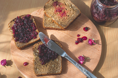 新鲜出炉的自制健康面包与黑醋栗果酱从花园里的新鲜有机水果自制果酱。在仿古装饰水果果酱在木桌背景上。完美甜蜜的早餐