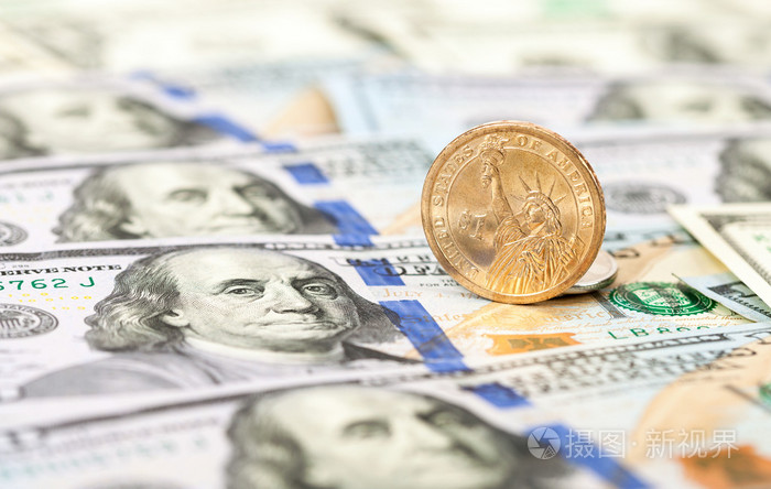 一个美国的美元硬币躺在一百美元的钞票