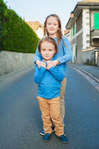 两个可爱的孩子们在一座城市，女孩和她的小弟弟，穿着蓝色和米色的衣服和皮鞋