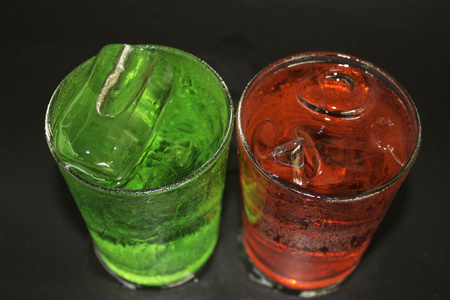 红色和绿色的水和冰在黑色背景上的玻璃