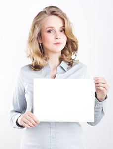 一件蓝色的衬衫，白色背景上孤立的美丽的商业女人。美丽的金发美女。白色的床单。女孩抱着一张白色纸
