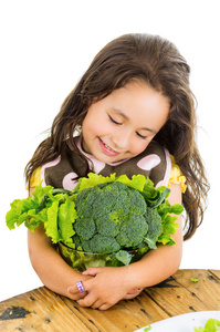 可爱健康的小女孩抱着西兰花和生菜沙拉碗