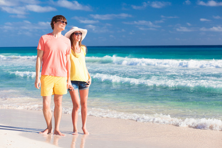 幸福的夫妇在海滩上太阳镜前面观