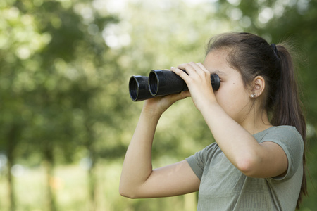 年轻漂亮的女孩，探索环境用双筒望远镜