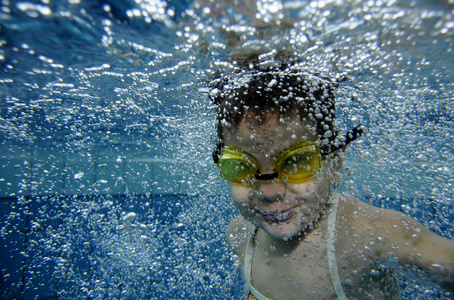 洗浴泡池尺寸有趣的快乐幼儿女孩水下与大量的空气泡在游泳池里游泳