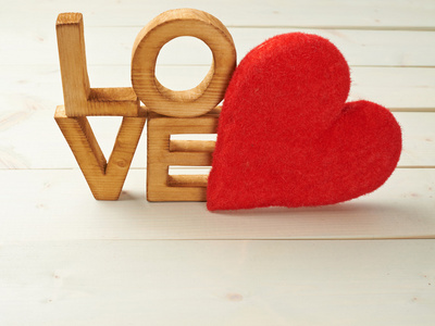 在彩色木质背景上用绿叶,鲜花和"爱"字组成在一个木表婚礼设置的字母