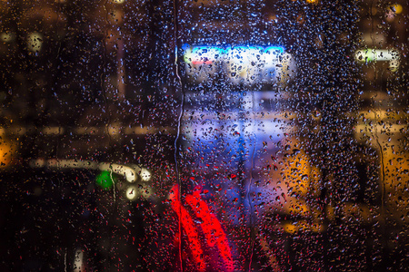 城市夜景灯光的玻璃窗上的雨点图片