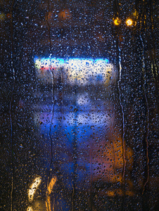 城市夜景灯光的玻璃窗上的雨点图片