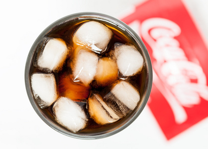 杯可口可乐甜不健康饮料与泡沫 冰块和徽标