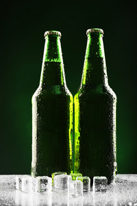 玻璃瓶装啤酒冰块上深绿色的背景