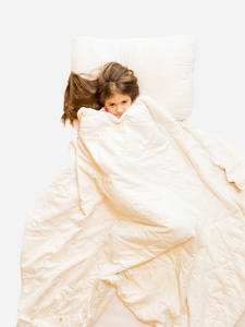 孤立的女孩躺在床上，用毯子盖的照片