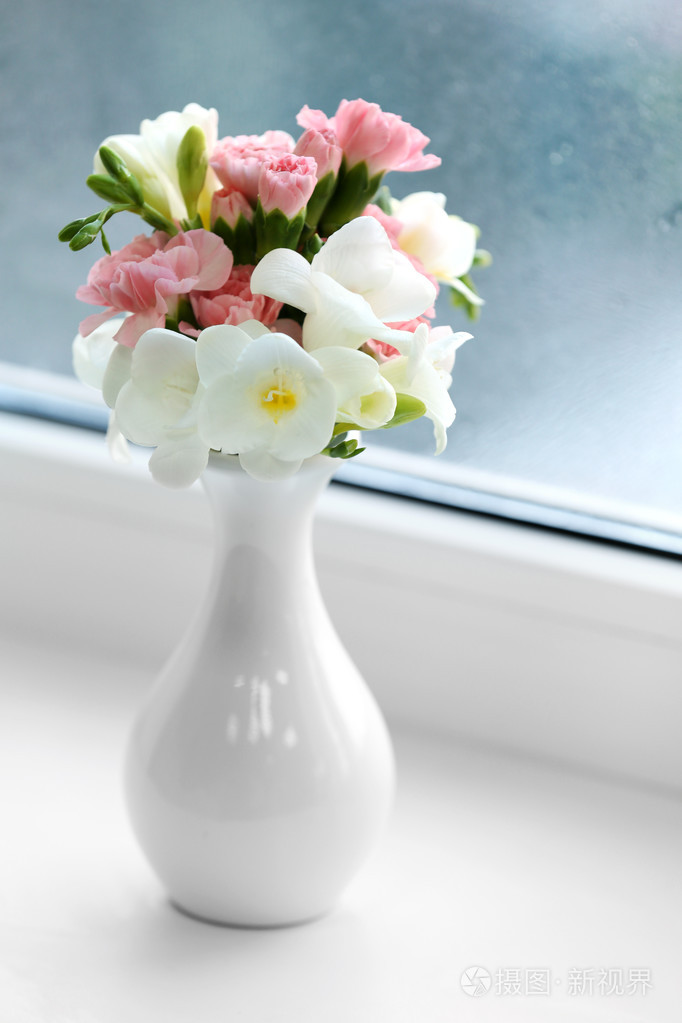 美丽的春天花在花瓶放在窗台上背景