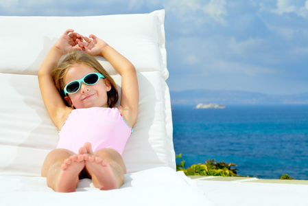 幼儿女孩对日光浴浴床赤脚的女人和长的衣服打扫指已提到的人道路在的