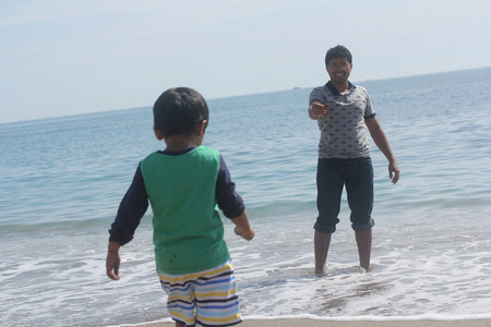 印度的父亲和儿子在风平浪静的大海海里玩水浪