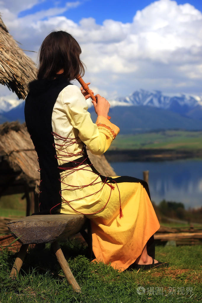 一个漂亮的女孩在她的长笛演奏中开放的景观加湖历史服装